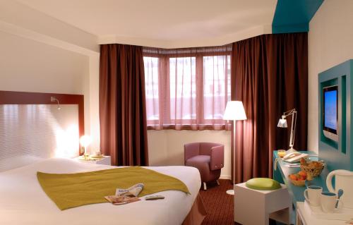 a hotel room with a bed and a chair at Mercure Strasbourg Centre in Strasbourg