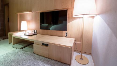 a room with a desk with a television and a lamp at Rian Hotel in Seoul