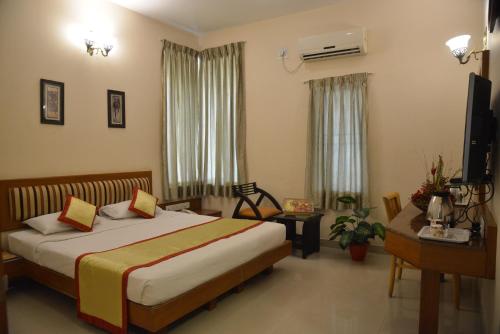 a bedroom with a bed and a desk and a television at Pai Vista, KR Road in Bangalore