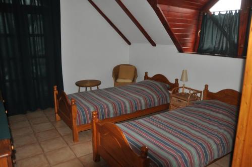 a bedroom with two beds and a chair at Berek Fogadó in Mátranovák