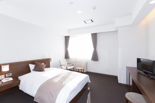 a hotel room with a bed and a tv at Kiyosato Onsen Hotel Ryokuseisou in Kiyosato