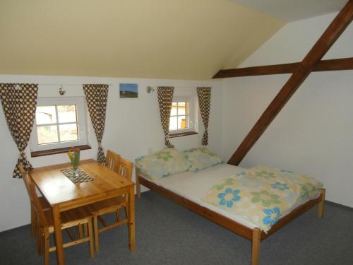 a bedroom with two beds and a wooden table at Penzion Zemanův Dvůr in Božanov