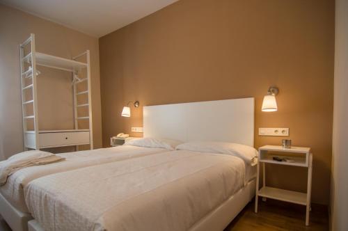 a bedroom with a large white bed and two lights at Hotel Los Cigarrales in Toledo