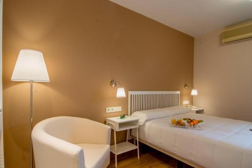 a hotel room with a bed and a chair at Hotel Los Cigarrales in Toledo