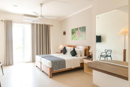 a white bedroom with a bed and a window at Twenty-Two Weligambay in Weligama
