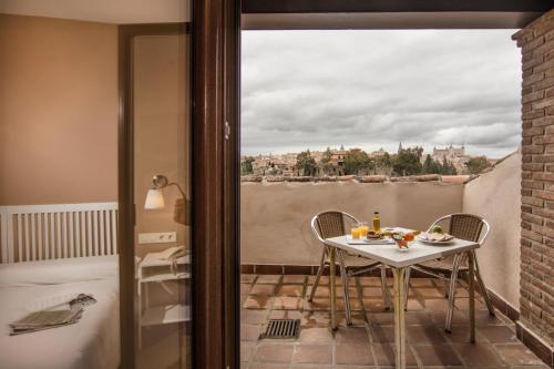 a room with a balcony with a table and chairs at Hotel Los Cigarrales in Toledo