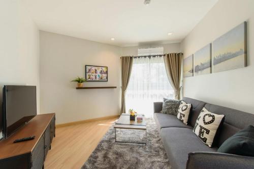 a living room with a gray couch and a tv at Urban Maerim in Mae Rim
