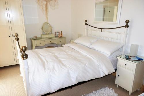 a bedroom with a white bed and a mirror at The White House in Padstow