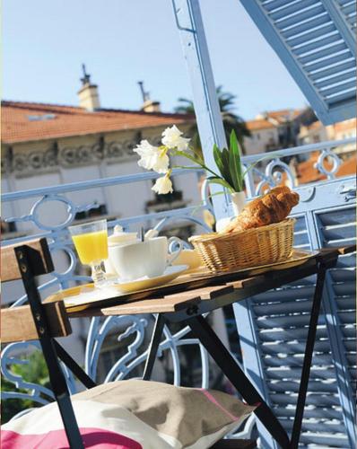 a table on a balcony with drinks and a basket of food at Villa Saint Hubert in Nice