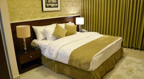 a large bed in a hotel room with two lamps at City Rose Hotel Suites in Amman