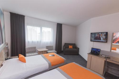 a hotel room with two beds and a television at Hotel Le Paddock in Magny-Cours