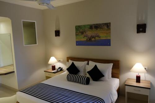 a bedroom with a bed with two night stands and two lamps at Twenty-Two Weligambay in Weligama