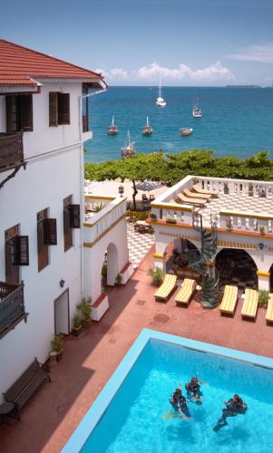 a view of a hotel with a swimming pool and the ocean at Tembo House Hotel in Zanzibar City