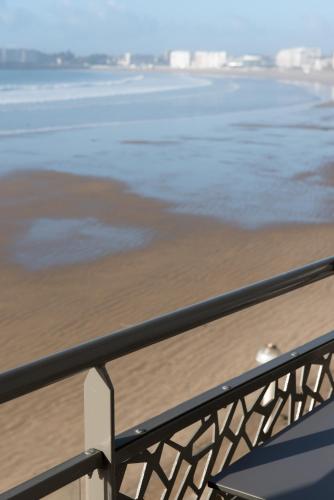 a balcony with a view of the beach and the ocean at Hotel & Spa Les Roches Noires in Les Sables-dʼOlonne