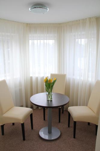 a room with a table and two chairs and a vase of flowers at Dzintars Hotel in Jūrmala
