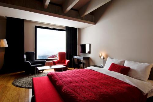a bedroom with a red bed and a large window at Golden Key Kartalkaya in Kartalkaya