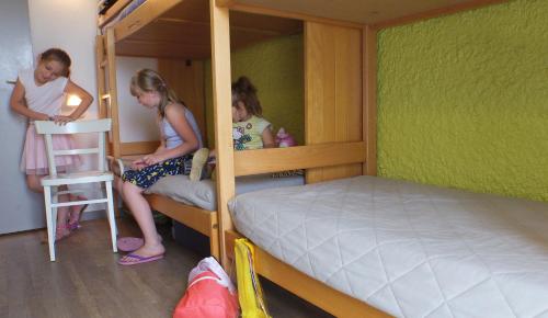 VVF Cotentin Îles anglo-normandes في بورتبايل: ثلاث فتيات يجلسن على سرير بطابقين في غرفة