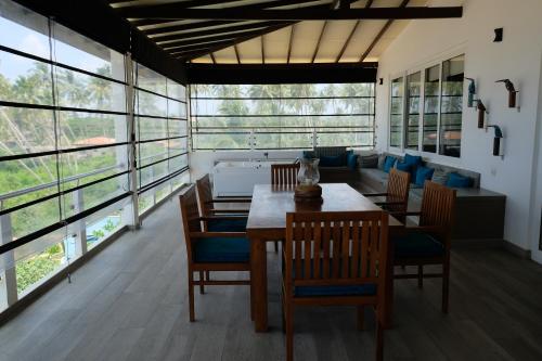 a dining room with a table and chairs and a couch at Twenty-Two Weligambay in Weligama
