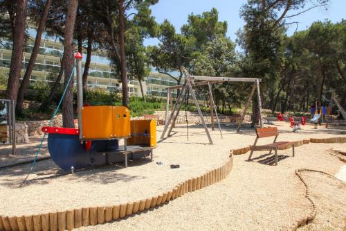 a playground with a swing set and a chair at Hotel Aurora in Mali Lošinj