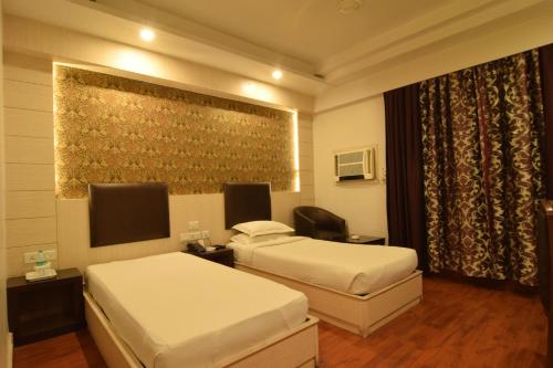 a hotel room with two beds and a television at Hotel The Sojourn in Kolkata