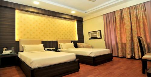 a hotel room with two beds and a desk at Hotel The Sojourn in Kolkata