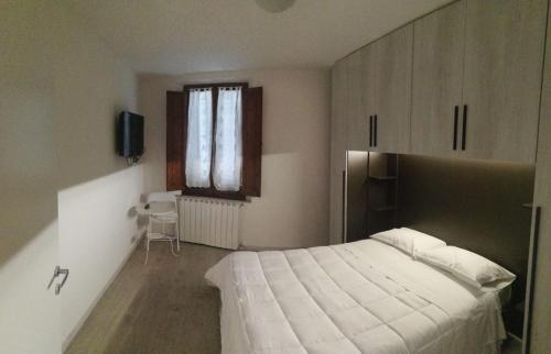 sypialnia z białym łóżkiem i oknem w obiekcie Alfredo's House w Sienie