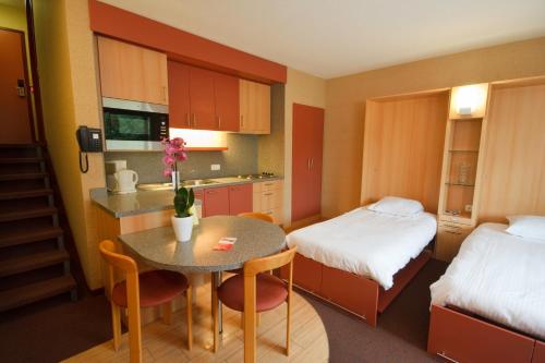 a small room with a kitchen and a table and a bed at Floreal Nieuwpoort in Nieuwpoort