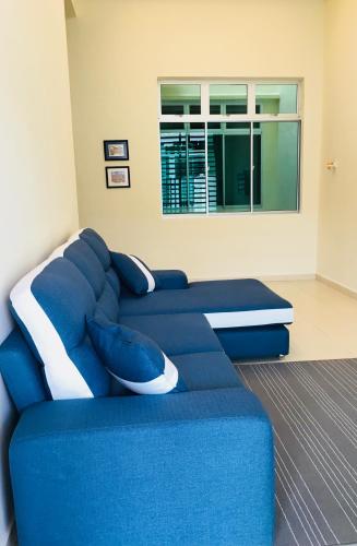 ein blaues Sofa in einem Zimmer mit Fenster in der Unterkunft Louie Homestay Mersing in Mersing