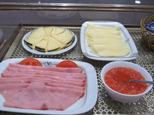 Una mesa con platos de queso y carne y salsa. en Hotel La Lanzada, en A Lanzada