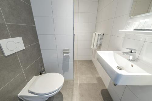 a white bathroom with a toilet and a sink at Van der Valk Texel - De Koog in De Koog