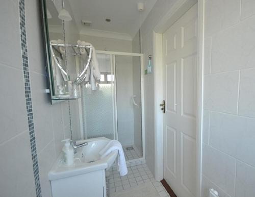 a white bathroom with a sink and a shower at Heritage Accommodation in Dundalk