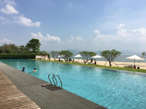 uma piscina ao lado de uma praia com guarda-sóis em HuiZhou HuaYangNian Seaview Guesthouse em Huidong