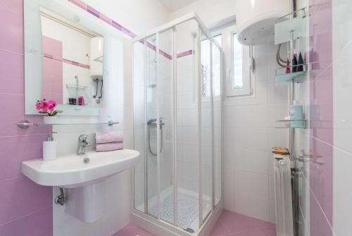 uma casa de banho com um lavatório e um chuveiro em Allegro em Rabac