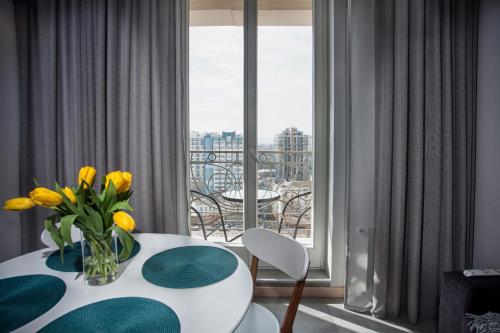 um quarto com uma mesa com um vaso de flores amarelas em Apartments Belietazh em Odessa