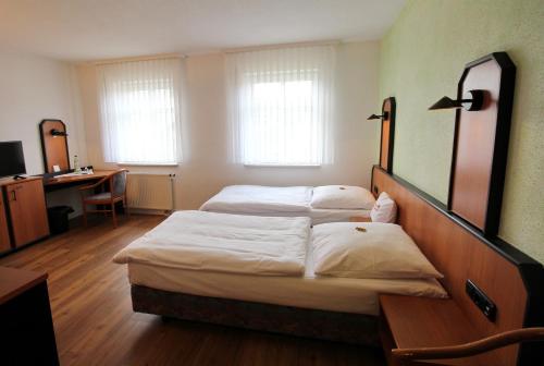 a hotel room with two beds and a desk at Hotel & Restaurant am Rosenhügel in Jüchsen