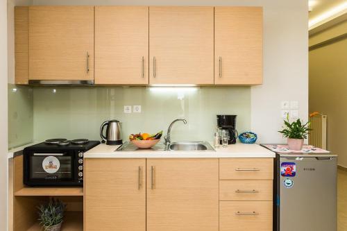 a kitchen with wooden cabinets and a sink and a microwave at Alektor Luxury Apartments in Zakynthos Town