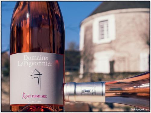 a bottle of wine with a building in the background at Le Pigeonnier in Saint-Martin-le-Beau