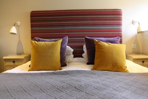 a bed with yellow and purple pillows on it at The Falstaff in Canterbury in Canterbury