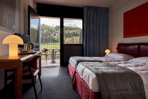 a hotel room with two beds and a desk and a window at Albornoz Palace Hotel in Spoleto