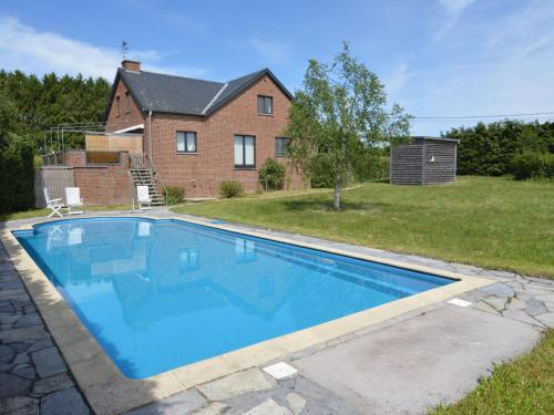 a large blue swimming pool in front of a house at Apartment with pool and sauna in Felenne