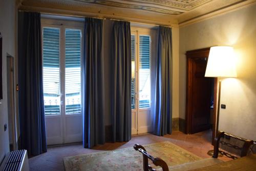 a room with windows with blue curtains and a lamp at Palazzo Tucci Residenza d'epoca in Lucca