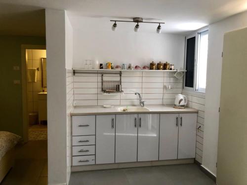 a white kitchen with a sink and a window at Tamar's House in Arad