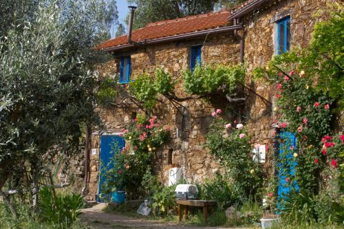 an old stone house with blue doors and flowers at Guest Room Agro-turismo Quinta da Fonte Bed&Breakfast in Figueiró dos Vinhos