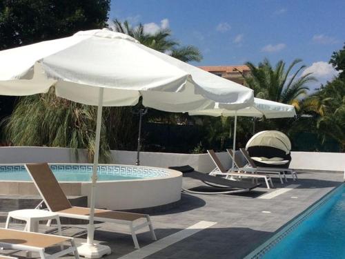 Un grupo de sillas y sombrillas junto a una piscina en Villa in Moriani-Plage near Sandy Beach, en San-Nicolao