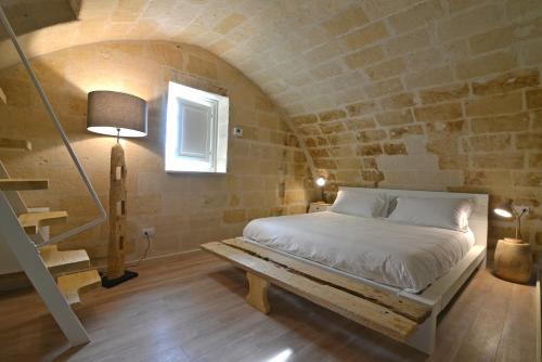 una camera con un letto in una parete in pietra di Comera a Matera