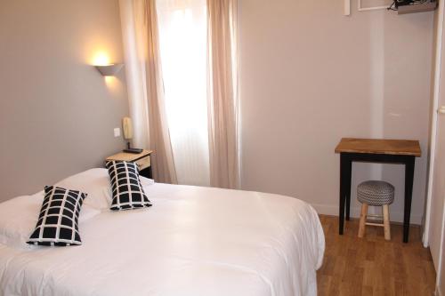 a bedroom with a white bed with two pillows on it at Les Glycines in Remoulins