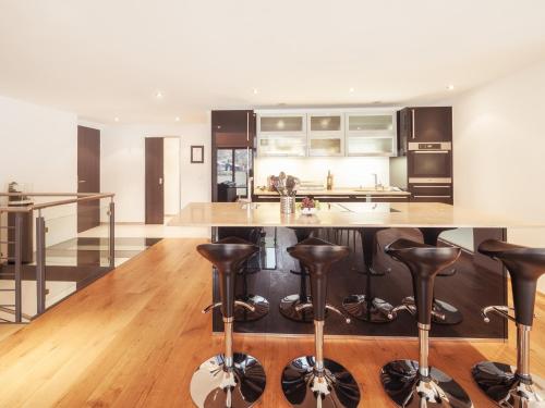 a kitchen with a large island with leather bar stools at Chalet Nepomuk in Zermatt