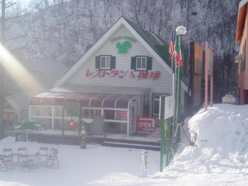 a building in the snow with tables and chairs at Green Grass Hakuba in Hakuba