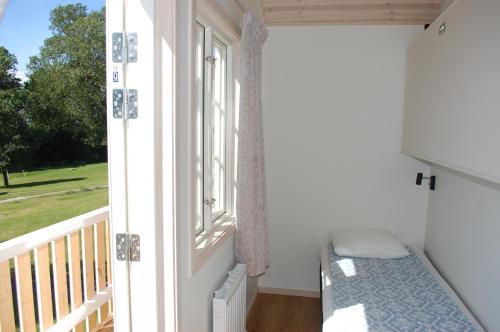 a room with a window with a bed and a balcony at Allégården Kastlösa Stugor in Mörbylånga