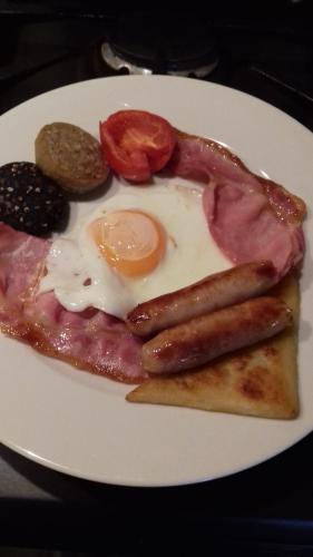 a plate of breakfast food with sausage and eggs at Ashfield B&B in Kenmare
